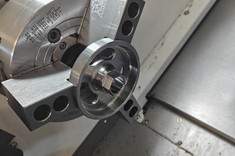 Zamocowany w uchwycie tokarskim element po obróbce, z widocznymi rowkami i precyzyjnie wykonanymi powierzchniami,